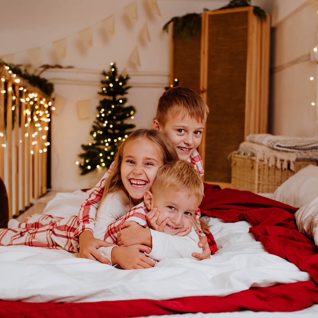 Three children smiling in their matching christmas pyjamas